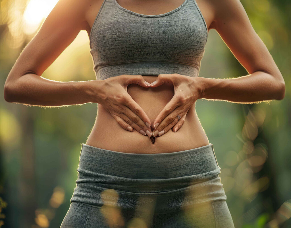 Ragazza in mezzo alla natura forma un cuore con le mani di fronte al suo addome
